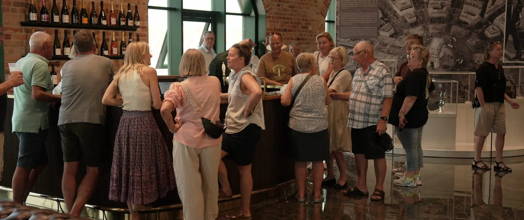 En masse mennesker der står inde i museet med en bar i baggrunden.